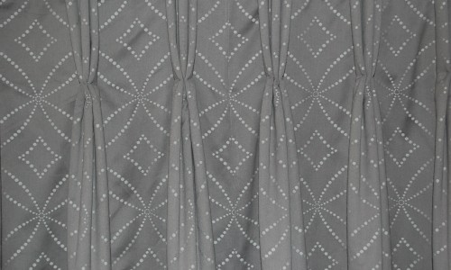 Photo showing an image of a triple pleat hand sewn curtain heading on geometric fabric