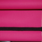 Photograph of a roller blind in a bright pink plain fabric with black piping along bottom bar