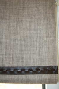 Photograph of a roller blind with a leather style trim across bottom edge